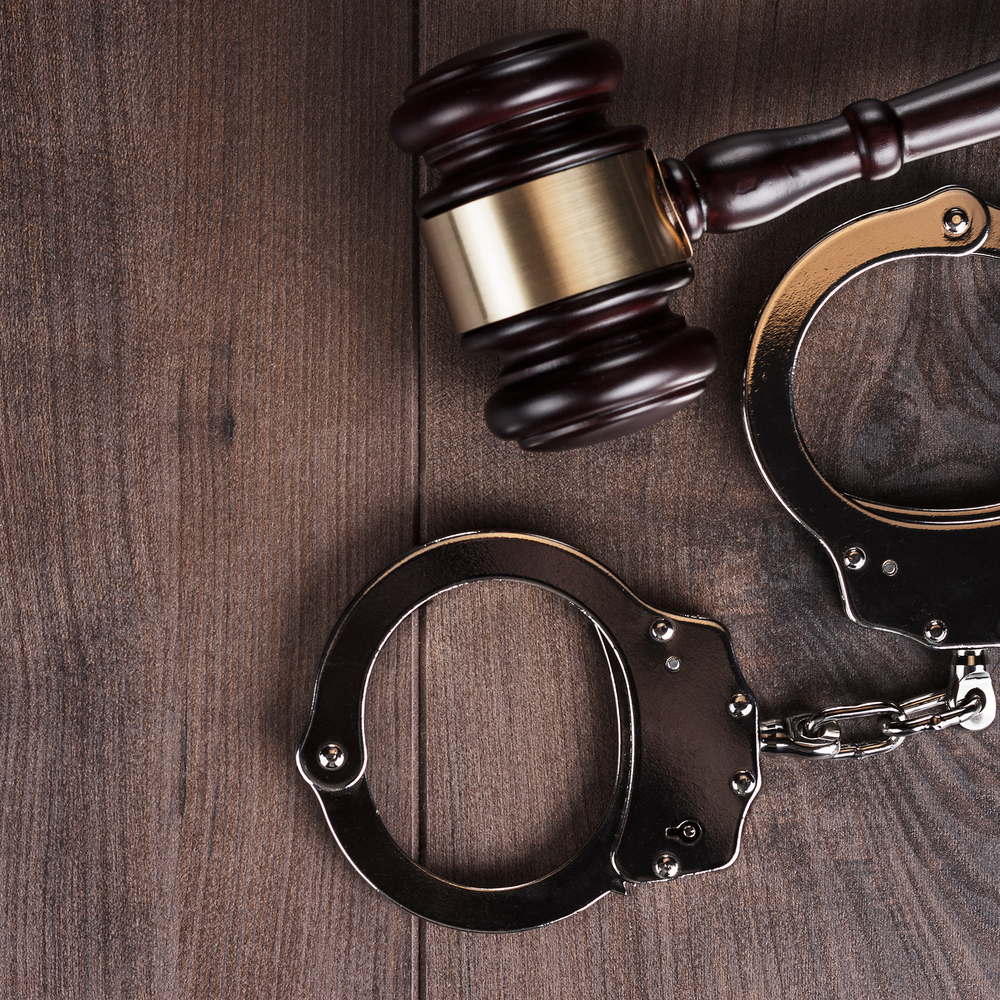 handcuffs and judge gavel on wooden background
